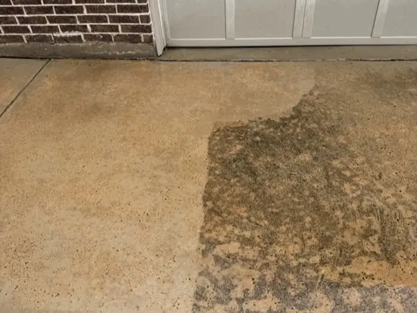 Stained driveway slab, half cleaned to show the difference