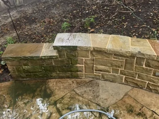 Stone wall mid-clean, half cleaned to show the difference